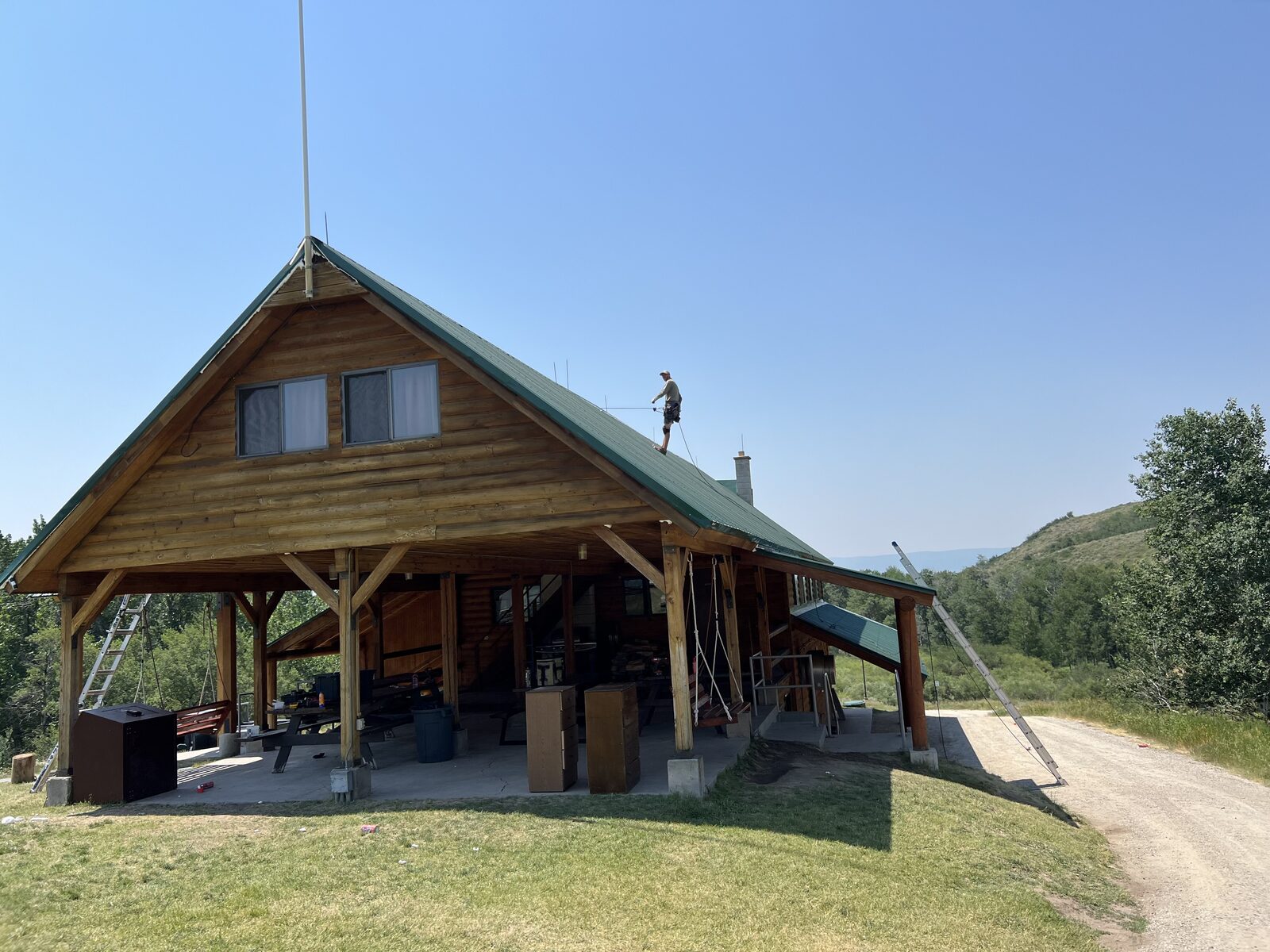 Jackson Hole Bat Removal technician working on the roof of a log lodge in a mountain meadow